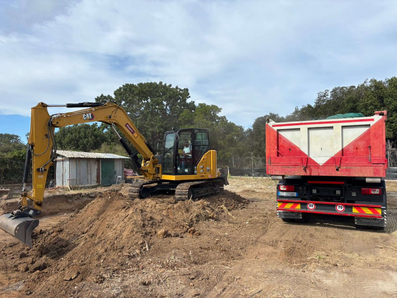 Caterpillar CAT 309 mini excavator rented from Alayan Rentals excavating and loading earth onto a dump truck Alayan Alquileres