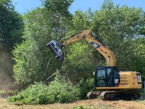 Testata trinciante forestale idraulica montata su escavatore cingolato Caterpillar CAT 318F L in opera per trinciatura alberi a noleggio Alayan Rentals