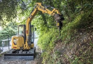 Hydraulic auger drive mounted on a Caterpillar CAT 305E2 CR mini excavator drilling ground on a slope for rent – Alayan Rentals