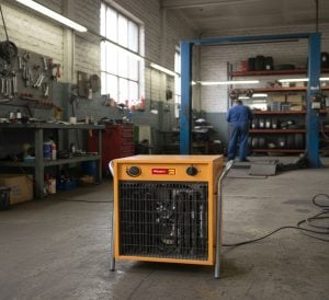 Yellow Master B 15 EPB three-phase electric fan heater in the foreground of a mechanical workshop for rent – Alayan Rentals