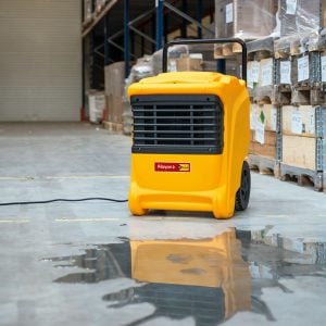 Gelber professioneller mobiler Luftentfeuchter Master DHP 65 beim Trocknen von Wasserlachen in einer Lagerhalle zur Miete – Alayan Rentals