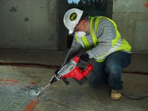 Bediener mit Helm und Maske beim Einsatz eines gemieteten 7kg Abbruchhammers von Alayan Rentals