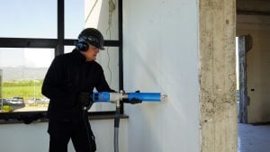 Operator wearing helmet and hearing protection using a dry hand-held core drill for rent by Alayan Rentals