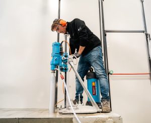Operator with Hydrostress rig-mounted core drill for wet drilling of concrete for rent by Alayan Rentals