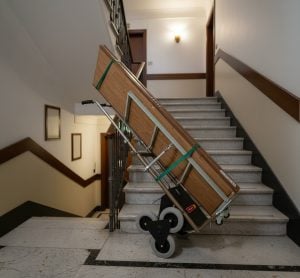 Electric stair climber hand truck for moving for rent by Alayan Rentals loaded with wooden planks on stairs
