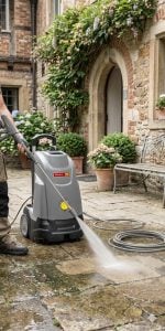 Operatore al lavoro con un'idropulitrice professionale ad acqua calda a noleggio Alayan Rentals su una pavimentazione esterna in pietra