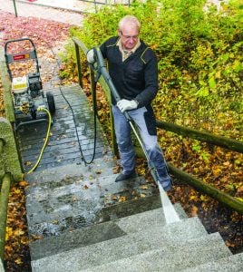 Operatore con occhiali di protezione mentre pulisce una scalinata in pietra con un'idropulitrice a scoppio ad acqua fredda a noleggio Alayan Rentals