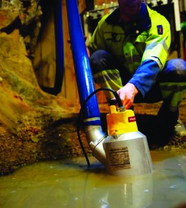 Bauarbeiter positioniert eine Miet-Tauchpumpe 850L der Weda-Serie von Alayan Rentals zur Wasserentwässerung
