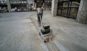 Operator at work with TR200 single-phase concrete scarifier for rent by Alayan Rentals inside a warehouse