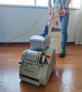 Bediener im Einsatz mit einer Bona Parkettschleifmaschine mit Staubsack