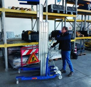 Operator maneuvering a manual material lift for rent by Alayan Rentals inside a warehouse