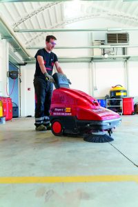 Bediener bei der Arbeit mit einer Handkehrmaschine zur Miete von Alayan Rentals in einer Halle