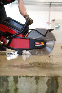 Operator working with a Milwaukee MX FUEL battery power cutter for rent by Alayan Rentals for wet cutting concrete