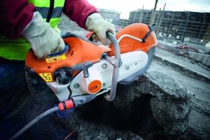 Construction worker using a hand-held petrol power cutter for rent by Alayan Rentals to cut concrete