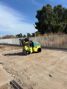 Ammann tandem roller with operator in action leveling soil, available for rent from Alayan Rentals