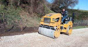 Caterpillar CB34B Tandemwalze im Einsatz auf einer Schotterstraße, mietbar bei Alayan Rentals