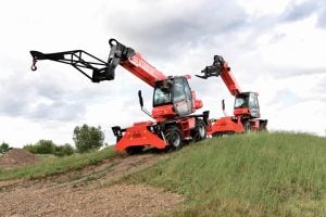 Due sollevatori telescopici rotativi Manitou rossi in cantiere all'aperto, uno con traliccio falconcino e gancio e uno con forche a noleggio Alayan Rentals