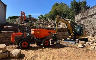 Dumper gommato Ausa D350AHG affiancato a miniescavatore Caterpillar in un cantiere di ristrutturazione a noleggio Alayan Rentals