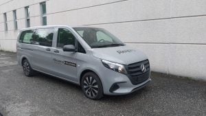 Minibus arancione Ford Transit Custom Active a noleggio Alayan Rentals parcheggiato in un paesaggio montano con alveo di fiume