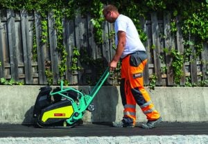Operatore al lavoro con una piastra vibrante Ammann per la compattazione dell'asfalto a noleggio Alayan Rentals