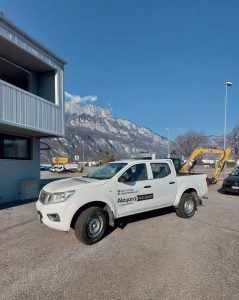 Pick-up bianco Nissan Navara a noleggio Alayan Rentals parcheggiato nel piazzale della sede con montagne sullo sfondo