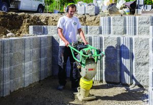 Bauarbeiter bei der Arbeit mit einem gemieteten Ammann-Vibrationsstampfer von Alayan Rentals zur Bodenverdichtung auf der Baustelle