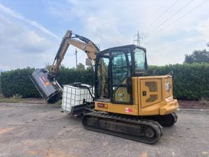 Gelber Caterpillar CAT 306 Raupenminibagger ausgestattet mit rotierender Solarmodul-Reinigungsbürste und Wassertank zur Miete – Alayan Rentals