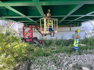 Red Hinowa LL14.70 tracked spider boom lift operating under a viaduct for high-altitude maintenance for rent – Alayan Rentals