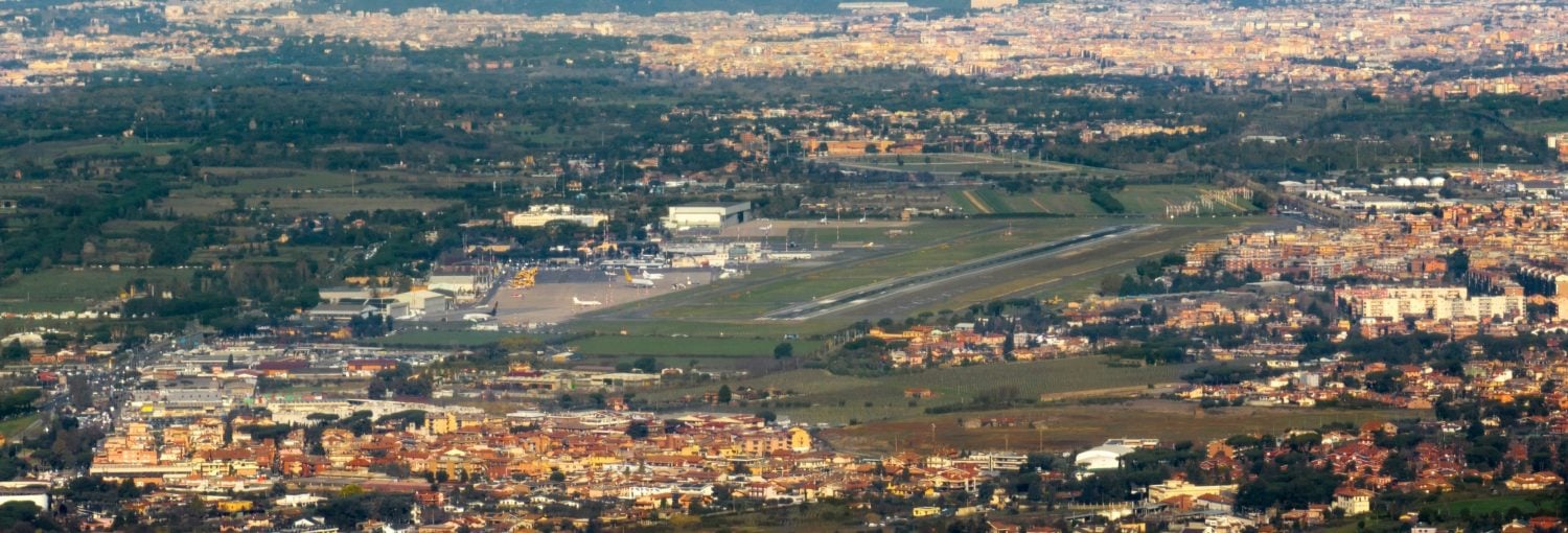 Vista aerea panoramica dell'Aeroporto di Roma Ciampino con pista di decollo, piazzale di sosta aeromobili, hangar e centro abitato circostante